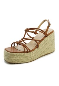 Bruine leren wedge sandaal met een geweven jute platform, voorzien van kruislings gespen en een gespsluiting. Glad oppervlak en open teen ontwerp.