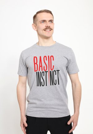 Grijze katoen t-shirt met korte mouwen, voorzien van vet donkerrode en zwarte tekst "BASIC INSTINCT" aan de voorkant. Eenvoudige, klassieke snit.