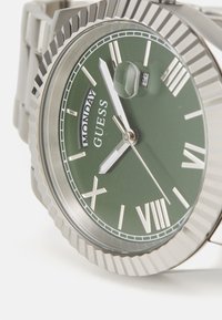 Edelstahlarmbanduhr mit grünem Ziffernblatt, weißen römischen Ziffern, Datumsanzeige und metallischen Akzenten. Verfügt über eine strukturierte Lünette und ein Gliederarmband.