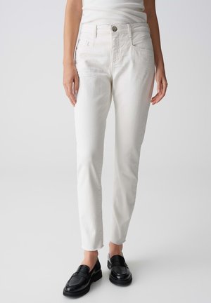 Witte spijkerbroeken van denim met een slim fit, rechte pijpen, een middelhoge taille en een ruwe zoom. Gecombineerd met zwarte instappers voor contrast.
