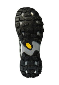 Suela de goma negra con surcos profundos, que presenta un logo de Vibram amarillo. El diseño incluye patrones texturizados variados para mejorar la tracción.