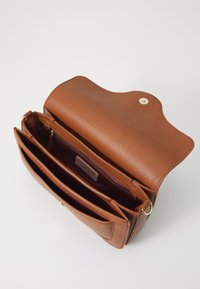Brown leather handbag with a textured surface, a flap closure, and a gold button. Interior features multiple compartments, including a zippered pocket.