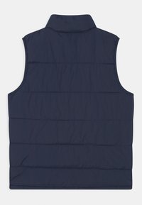 Granatowa kamizelka z ociepleniem i wysokim kołnierzem, z poziomym pikowaniem i bez rękawów. Lekki materiał i gładka tekstura.