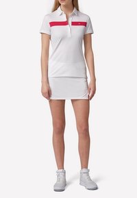 Biała koszulka polo z różowym poziomym paskiem, zestawiona z dopasowaną białą spódnicą. Materiał wydaje się gładki i lekki.