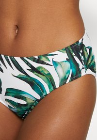 Parte de baixo de bikini com um fundo branco apresentando padrões de folhas tropicais verdes. Feita de um tecido suave e elástico, com um corte baixo e bordas costuradas.