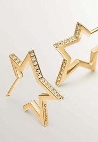 Pendientes en forma de estrella dorada con un diseño en zigzag, adornados con cristales de roca claros a lo largo de los bordes, acabado pulido y postes delgados.