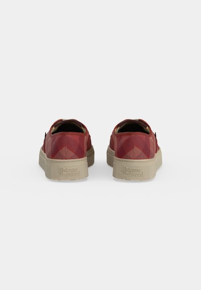 Ζευγάρι κόκκινα sneakers χαμηλού ύψους με μπεζ παχιά σόλα, εμφανιζόμενα από πίσω σε λευκό φόντο.