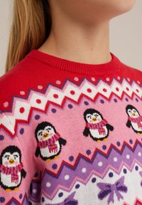 Rdeč pleten pulover z motivi pingvinov v šalih, cik-cak in pikčastih vzorcih v roza in vijolični barvi, s krožnim ovratnikom in rebrastimi manšetami.