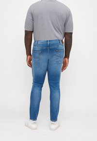 Slim fit jeans i medelblå denim, med femfickorsdesign, diskret blekning och en tan läderetikett på bakre midjan.