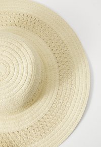 Sombrero de sol de paja de ala ancha en color beige claro, con un patrón tejido y textura suave, con una corona redondeada y ala plana.