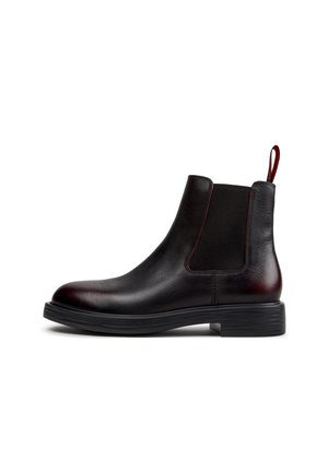 Schwarzer Chelsea-Lederstiefel mit elastischem Seitenteil, roter Naht, Zuglasche und niedrigem gestapeltem Absatz auf weißem Hintergrund.