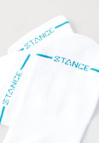 Bílé ponožky s tyrkysovým textem a pruhy "STANCE", se strukturovanou tkaninou, standardní délkou do kotníku a zesílenou špičkou.