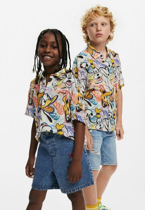 Camisas de mangas cortas y coloridas con personajes de dibujos animados y patrones abstractos, combinadas con pantalones cortos de denim y calcetines y zapatos multicolores.