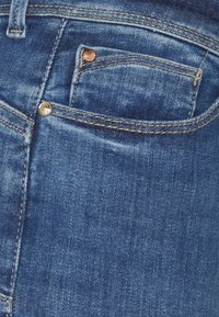 Jeans i medelblått denim med en något urtvättad finish. Innehåller en liten framficka och metallknappdetaljer. Texturerad tyg.