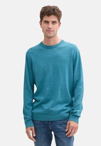 Türkisfarbener Pullover aus einem weichen, mittelschweren Strick. Beinhaltet einen runden Ausschnitt und lange Ärmel, mit gerippten Bündchen und Saum für zusätzliche Textur.