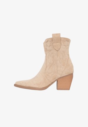 Beige suède cowboylaarzen met een pointed toe, decoratieve stiksel en een gestapelde hak. Heeft een trekband aan de achterkant.