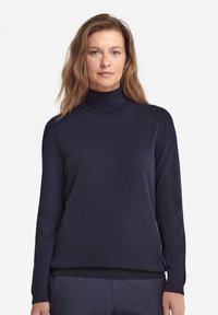 Navyblauer Rollkragenspullover aus weichem Strickstoff. Mit langen Ärmeln und einem lockeren Schnitt. Glatte Textur mit geripptem Kragen und Saum.