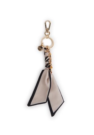 Portachiavi dorato con sciarpa di tessuto beige e nero, dettaglio catena dorata e piccolo charm rotondo.