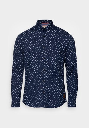 Camisa azul marino de manga larga con botones, estampada con patrón de rombos blancos y cuello clásico, presentada sobre un fondo liso.