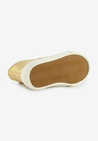 Semelle de sneaker de couleur or avec un bord en caoutchouc blanc. La semelle en gomme présente un motif en zigzag pour une meilleure traction. Texture douce avec des détails de couture subtils.