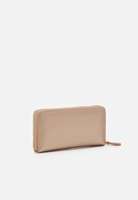 Portefeuille en or rose en cuir texturé, avec une fermeture éclair sur trois côtés et une petite tirette. Forme rectangulaire.