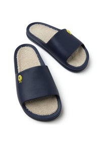 Zapatillas deslizantes de color azul marino con un acabado mate, interior de felpa beige y un pequeño personaje amarillo como acento en la correa.