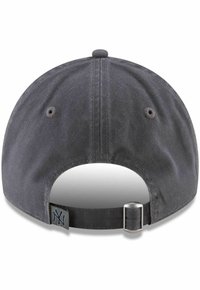 Grå baseballcaps med bøyd skygge, teksturert stoff, justerbar stropp bak, og et lite logoklipp nær stroppen.