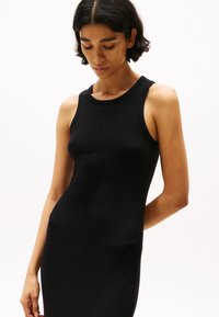 Abito a canotta nero a coste con una silhouette aderente. Presenta un colletto tondo e senza maniche, evidenziando una texture liscia e una vestibilità avvolgente.