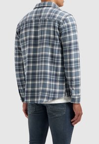 Blauw geruite flanellen overhemd met een button-down kraag, lange mouwen en witte accenten. Het materiaal lijkt zacht met een gestructureerde afwerking.