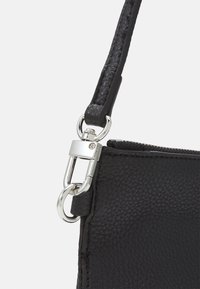 Czarna skórzana torebka z teksturowanym wykończeniem, zapięciem z metalu srebrnego i zamkiem błyskawicznym. Pasek jest pleciony dla lepszej przyczepności.