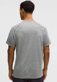 Tricou gri cu mâneci scurte, realizat dintr-un material texturat, cu decolteu rotund și mâneci raglan, având o croială lejeră și detalii subtile ale modelului.