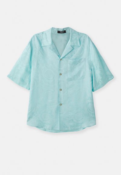 Šviesiai mėlynas trumpomis rankovėmis marškinėliai, pagaminti iš sklandžios medžiagos, su plačiu apykakle, priekinėmis kišenėmis ir subtiliu tekstūriniu raštu, su auksinėmis mygtukais.