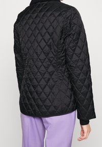 Czarna pikowana kurtka w diamentowy wzór, o miękkiej fakturze i kołnierzyku. Posiada długie rękawy i luźny krój.