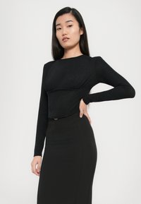 Zwarte lange mouwen crop top met een textuurafwerking, met een ronde halslijn en een aansluitende snit, gecombineerd met een hoge taille zwarte rok.