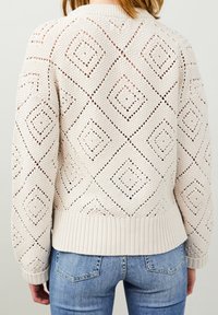 Maglione lavorato a maglia color beige chiaro con un design a rete aperta a motivo diagonale, polsini e orlo a coste, e una vestibilità rilassata. Ideale per essere indossato a strati.