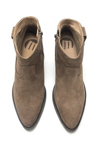 Botines de ante marrón con punta afilada, parte trasera abierta y costura decorativa. Incluyen una plantilla texturizada y suela de goma negra.