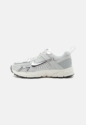 Baskets blanches et grises avec le logo Nike argenté réfléchissant, dessus en mesh et synthétique, semelle rembourrée et languette au talon.