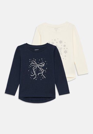 Conjunto de duas camisetas de mangas longas: uma em azul-marinho com gráfico de laço prateado e outra em creme com flocos de neve prateados. Algodão macio, com barras arredondadas.