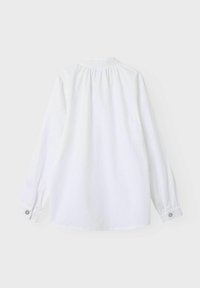 Camicia bianca a maniche lunghe con dettaglio arricciato sul retro, polsini con bottoni e orlo leggermente curvo. Realizzata in tessuto morbido e liscio.