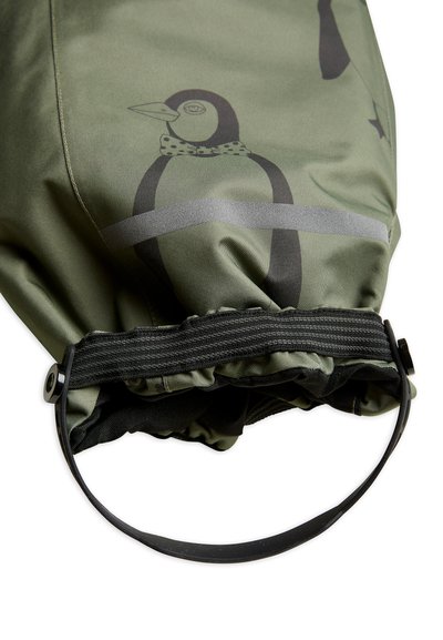 Žalia audinio maišelis su pingvino atvaizdu, elastingu raišteliu uždarymui ir juodu guminiu dirželiu. Ant maišelio yra pilkos horizontalios juostos ir tekstūruota paviršiaus struktūra.