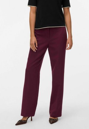Pantalons larges bordeaux en tissu lisse, présentant une coupe ajustée et sans motifs visibles. Associés à un haut noir et des talons marron.
