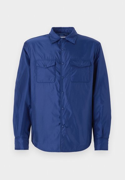 Chemise à manches longues bleu marine en tissu lisse et brillant ; dispose de deux poches à rabat, d'une fermeture à boutons et d'un col classique.