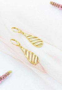 Orecchini pendenti in oro a forma di goccia, con design alternato di superfici lisce e striate, accentuati da piccole pietre chiare.