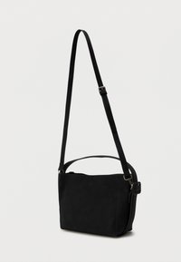 Sorte rektangulær crossbody taske med justerbar rem og kort håndtag på en ensfarvet lys baggrund.