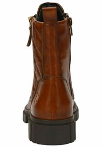 Stivale alla caviglia in pelle marrone con una texture trapuntata, zip sul retro e suola in gomma spessa. Caratterizzato da un pratico tirante corto sul tallone.