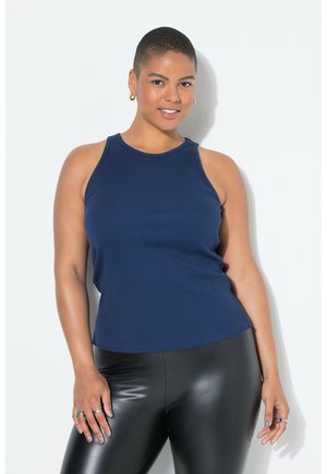 Top senza maniche di colore blu navy con scollatura rotonda, realizzato in tessuto a costine, abbinato a leggings neri lucidi e accessori minimal.
