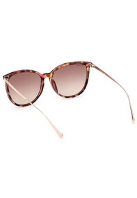 Gafas de sol estilo cat-eye con un patrón de carey, lentes marrones degradados y brazos metálicos elegantes en tono dorado.