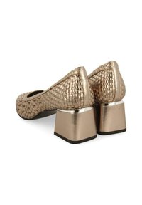 Bailarinas metálicas doradas tejidas con punta redonda, con un tacón cuadrado y acentos suaves. Superficie texturizada con un acabado brillante.