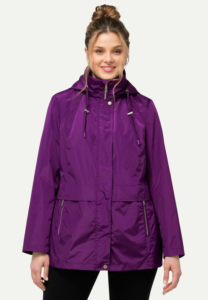 Lila vattentät jacka med huva, dragkedjefickor, justerbara dragsnoddar vid halslinningen och en avslappnad passform. Slät, glänsande tyg.