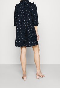 Marinblå klänning med ljusblå prickar, puffärmar och avslappnad passform, kombinerad med rosa blockklacksandaler.